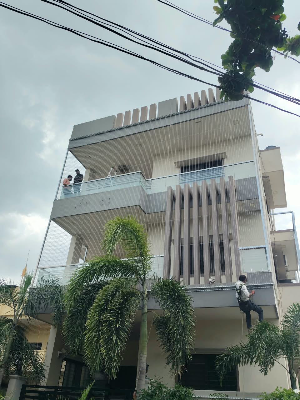 Installer on rope access fitting invisible grill cables to a building facade